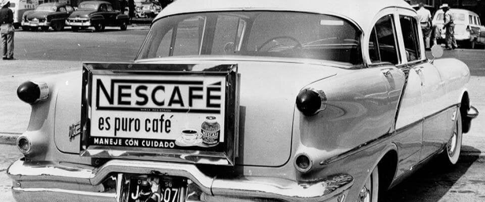 A car from the 1950s with an old Nescafé advert on its bumper