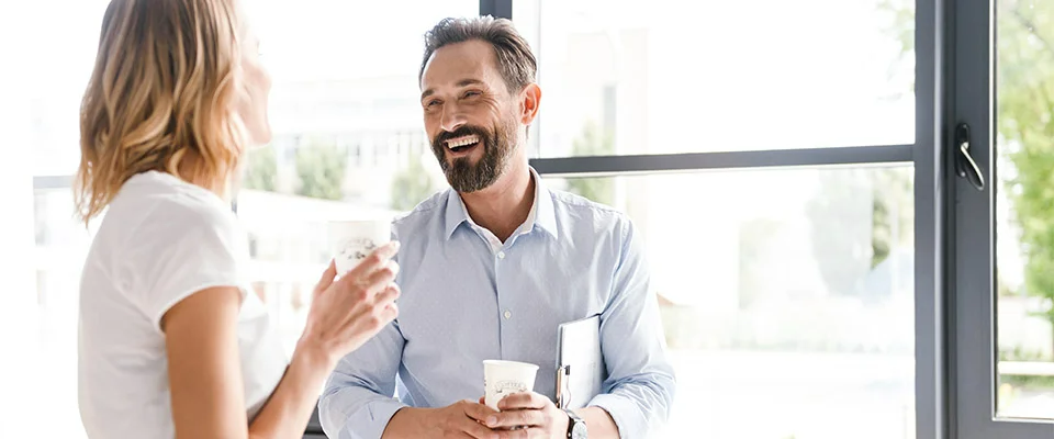 Work colleagues enjoying a conversation with hot beverages in hand