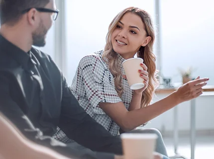 woman talking to a colleague holding a cup of coffee