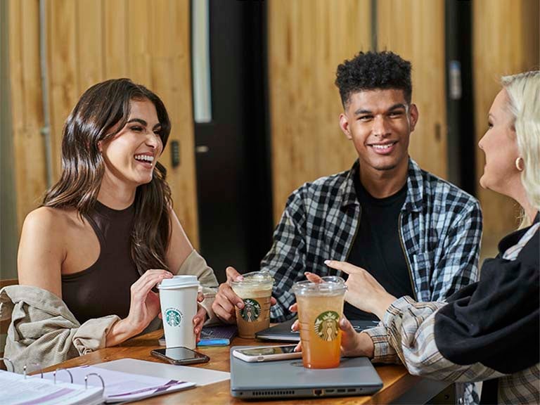 two students and one teacher drinking starbucks on campus