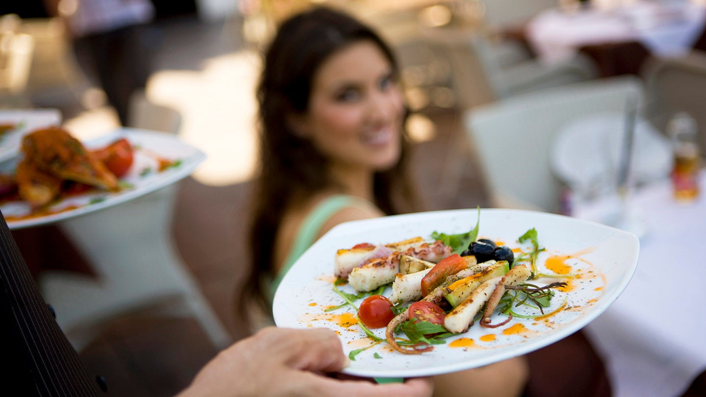 Waiter serving a dish to woman