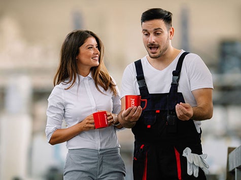 Two colleagues holding red Nescafé mugs and talking