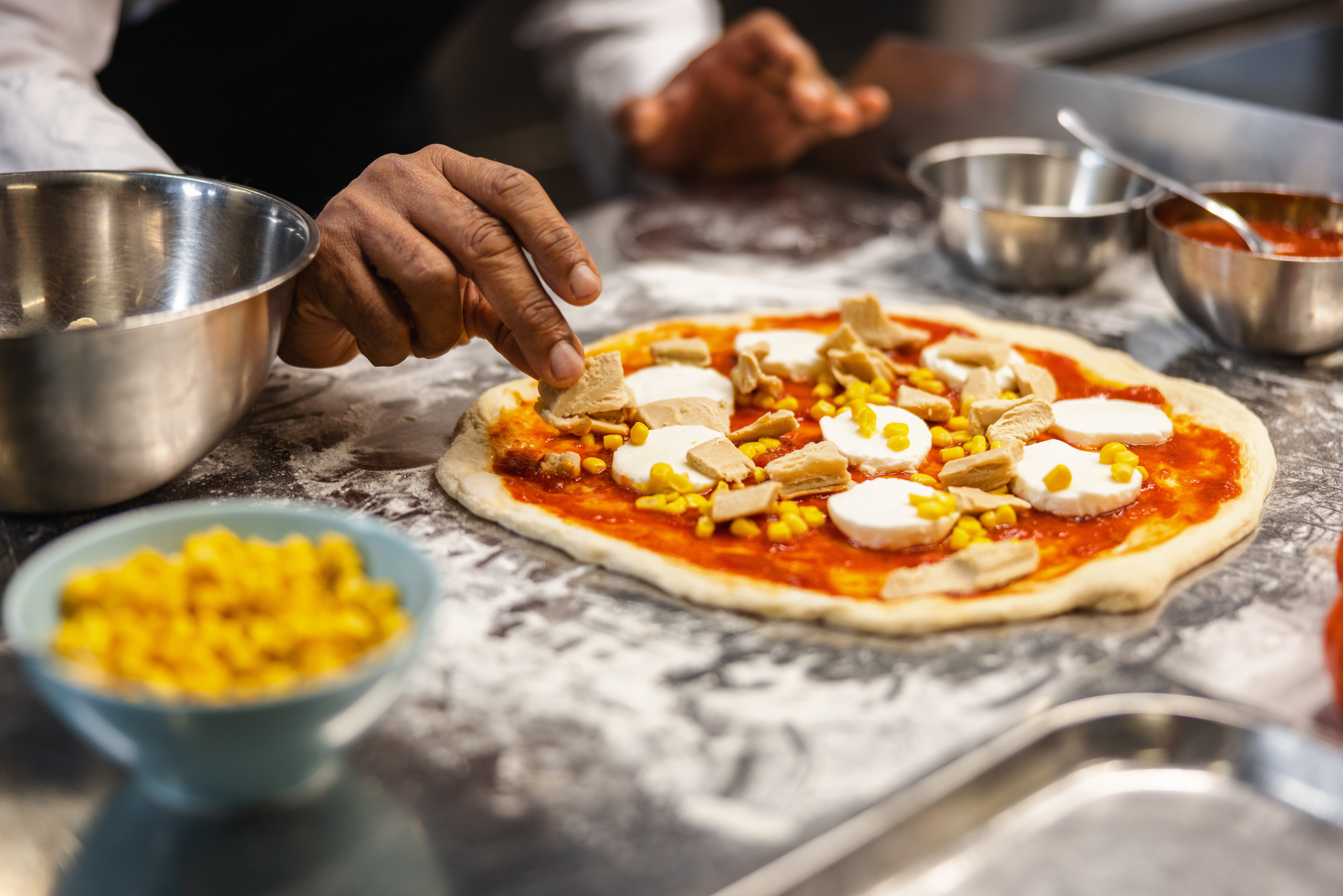 chef placing GARDEN GOURMET® vegan chicken-style fillet pieces on pizza