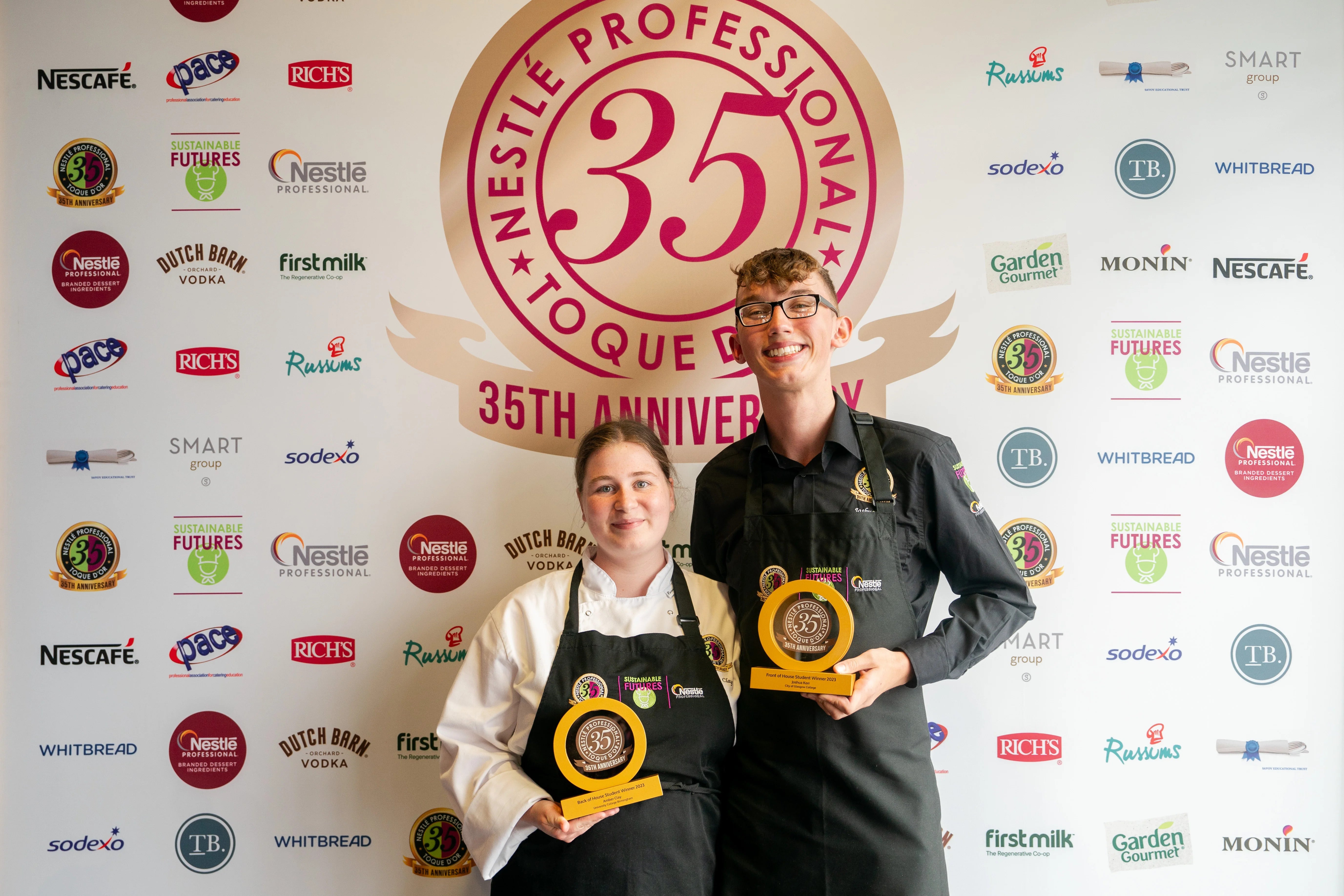 a-man-and-woman-holding-awards