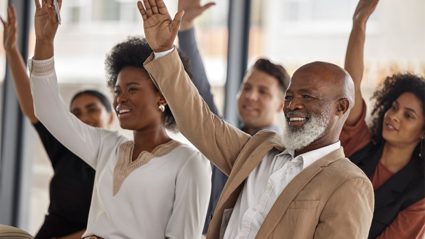 colleagues in a meeting raising their hands