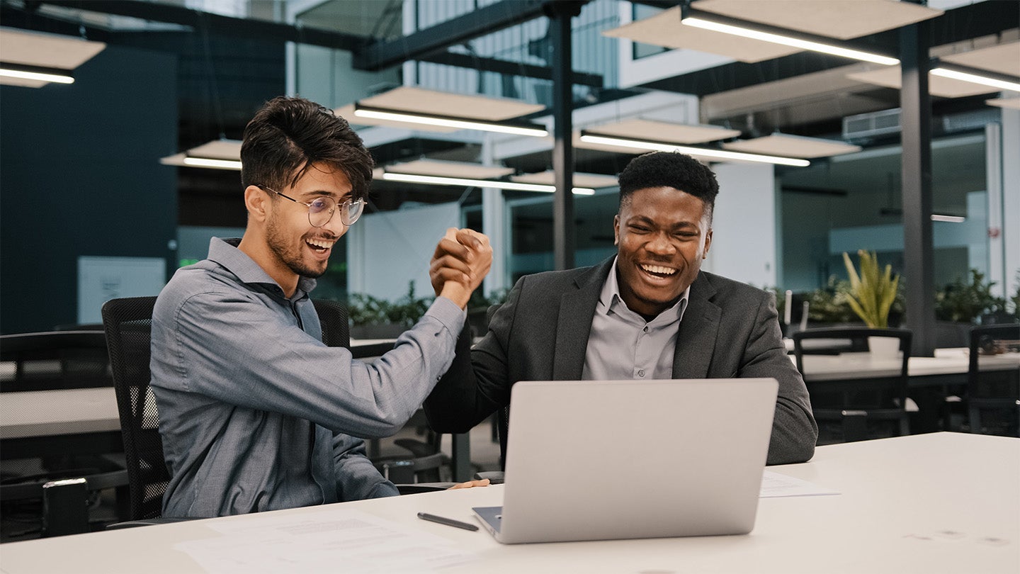 colleagues shaking hands looking at laptop