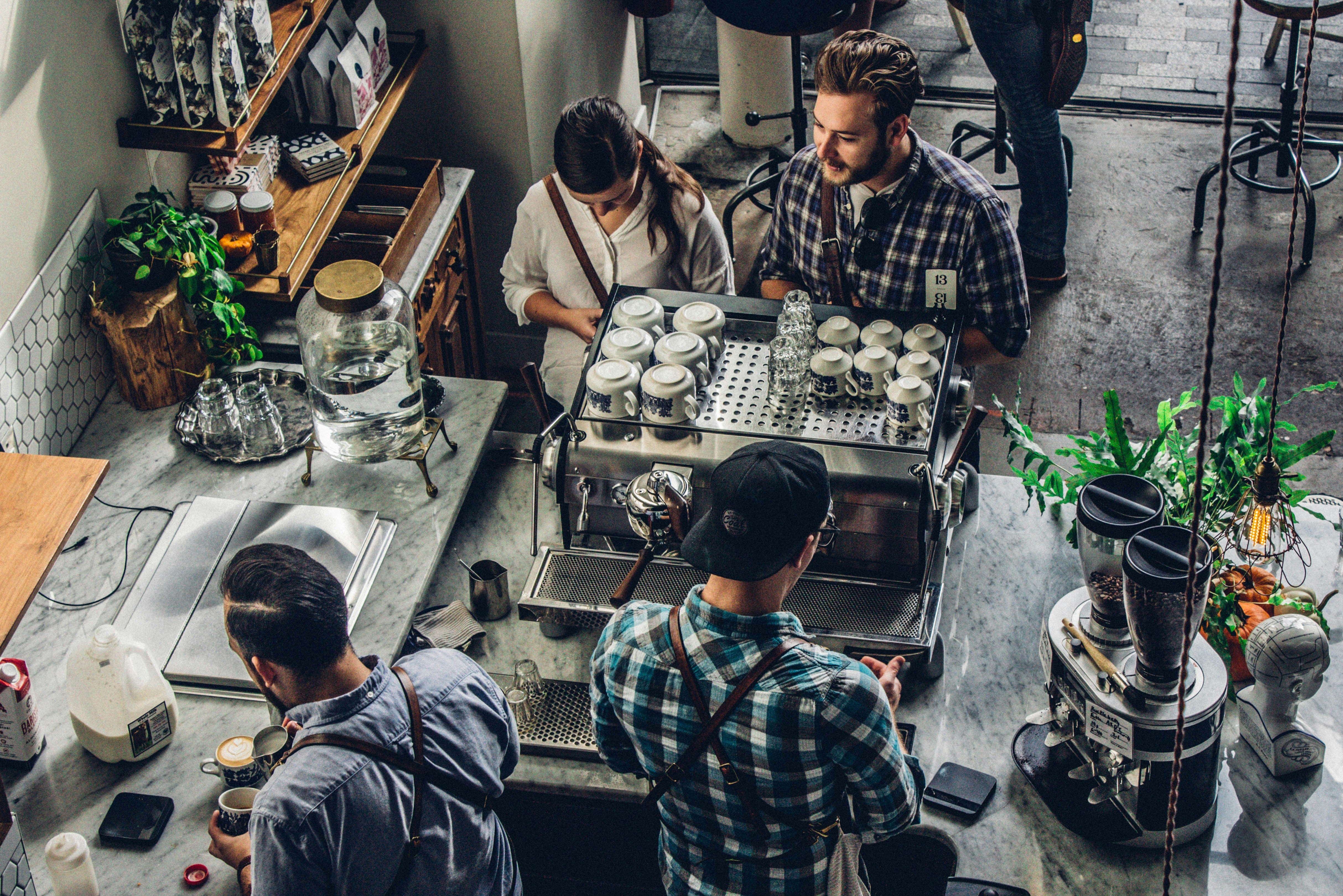 Two customers in a café standing by the coffee machine.