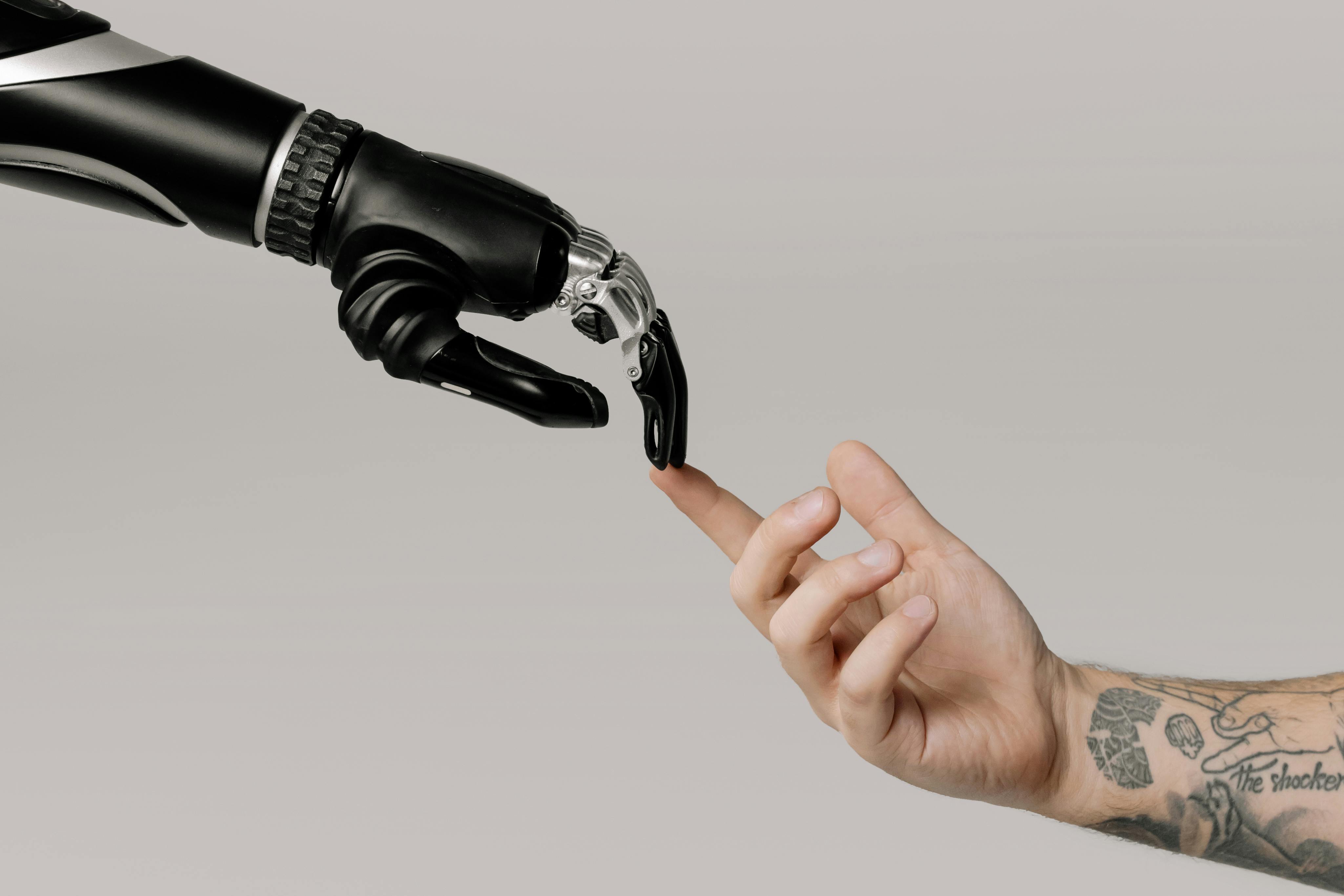 A human hand touching the finger of a robot’s hand.