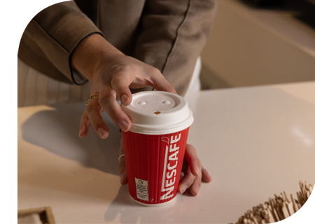 Hand holding a Nescafe on-the-go cup lid (made with fibre)