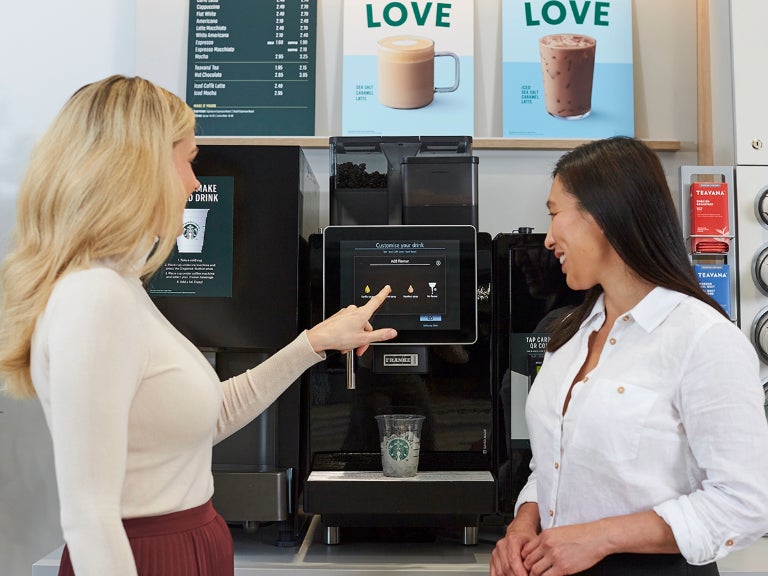 2 women getting coffee from machine