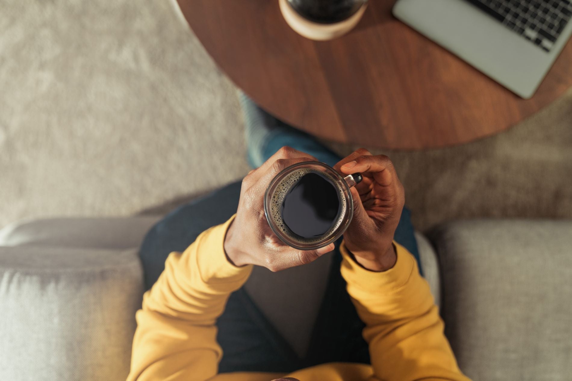 hand holding a mug of black coffee at a desk