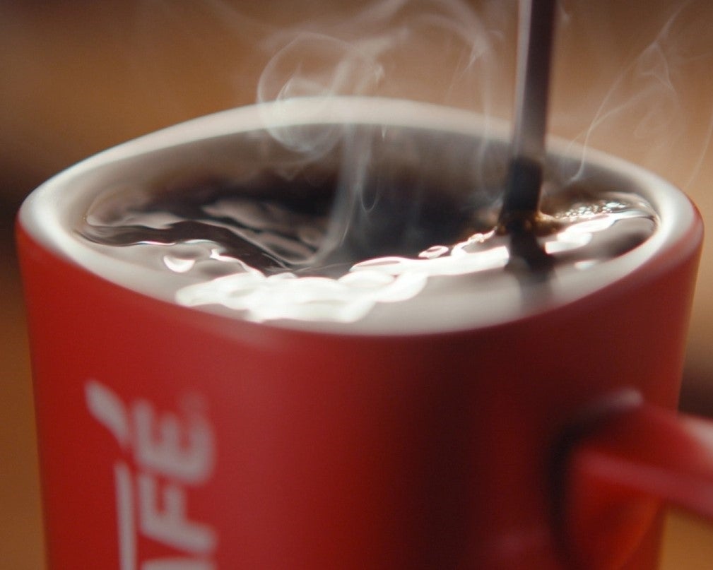 coffee being poured into red nescafe mug