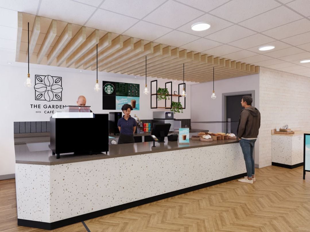 Modern café interior with a long terrazzo counter, baristas behind register, hanging lights, and a customer waiting to order.