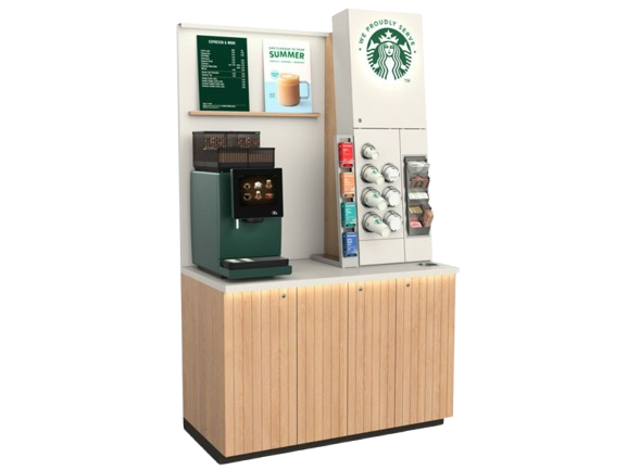 Starbucks self-serve coffee kiosk with espresso machine, syrup dispensers, cups, and promotional signage on a wooden cabinet