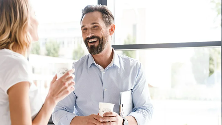 Work colleagues enjoying a conversation with hot beverages in hand