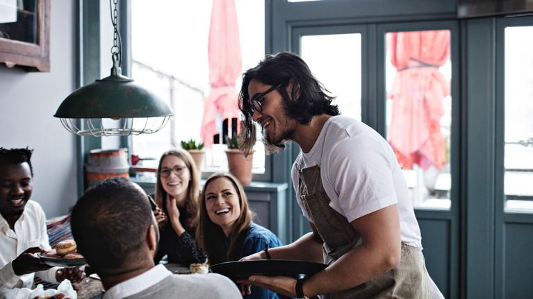 A waiter serving a group in a cafe