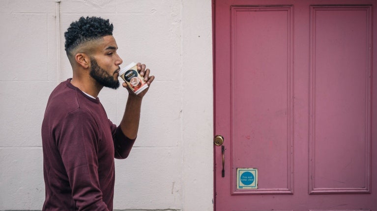 Man walking past door with coffee