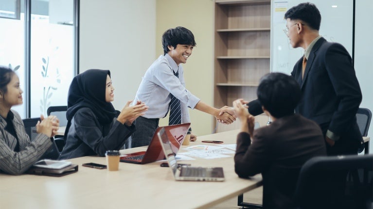 colleagues in a meeting shaking hands 