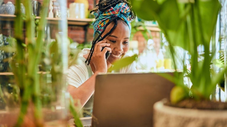 small business owner in front of her laptop and surrounded by plants