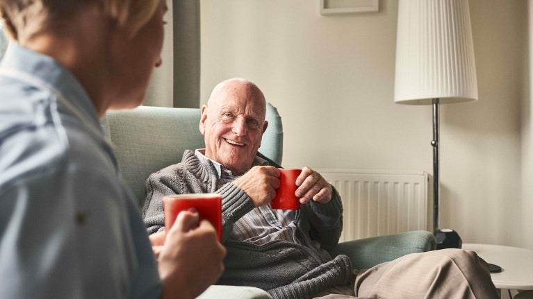Resident of a care home chatting with nurse whilst drinking nescafe instant coffee