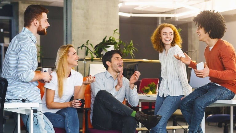 group of co-workers talking animatedly whilst drinking their coffee