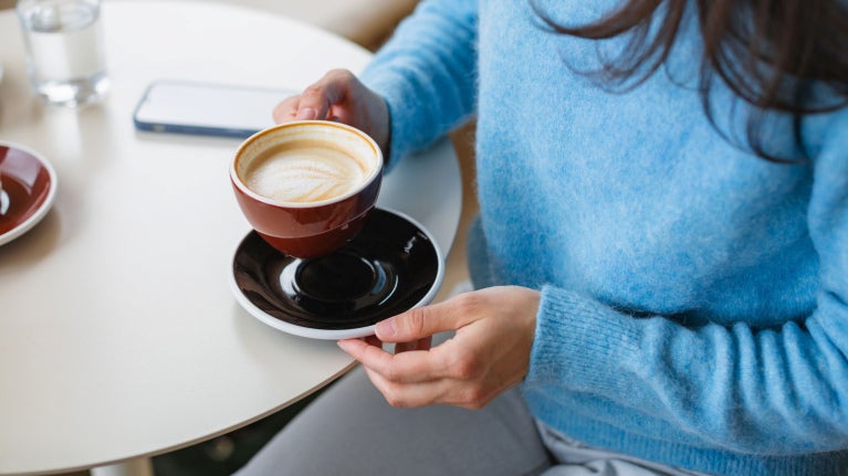 woman holding a flat white