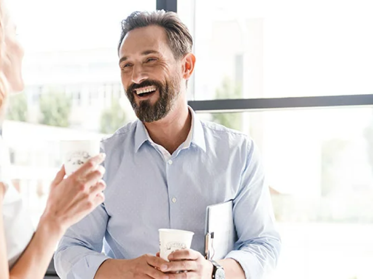 Work colleagues enjoying a conversation with hot beverages in hand
