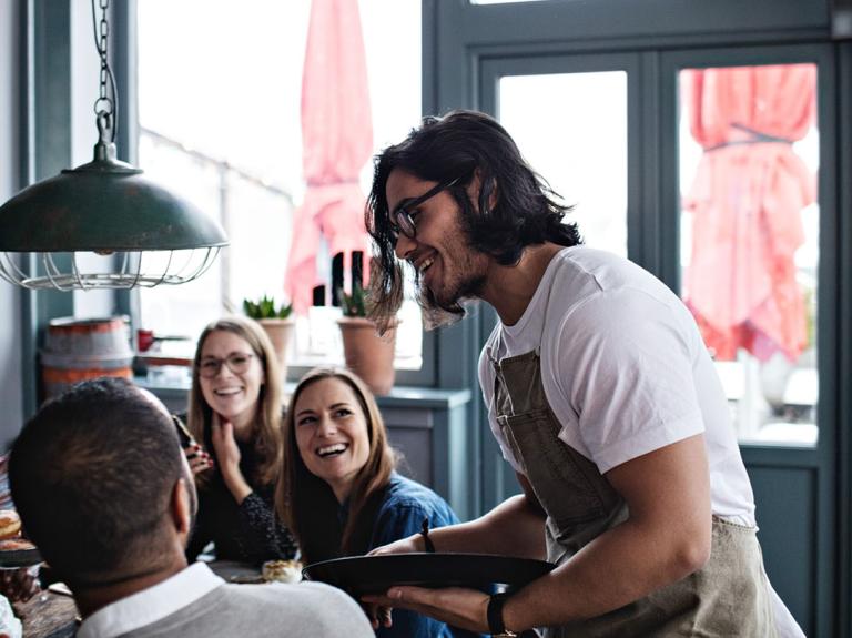 A waiter serving a group in a cafe