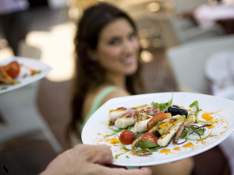Waiter serving a dish to woman