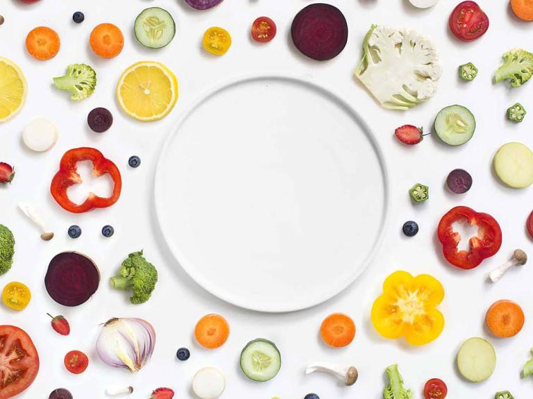 An empty plate surrounded by vegetables