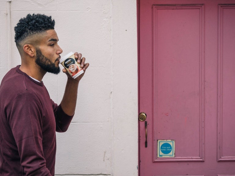 Man walking past door with coffee
