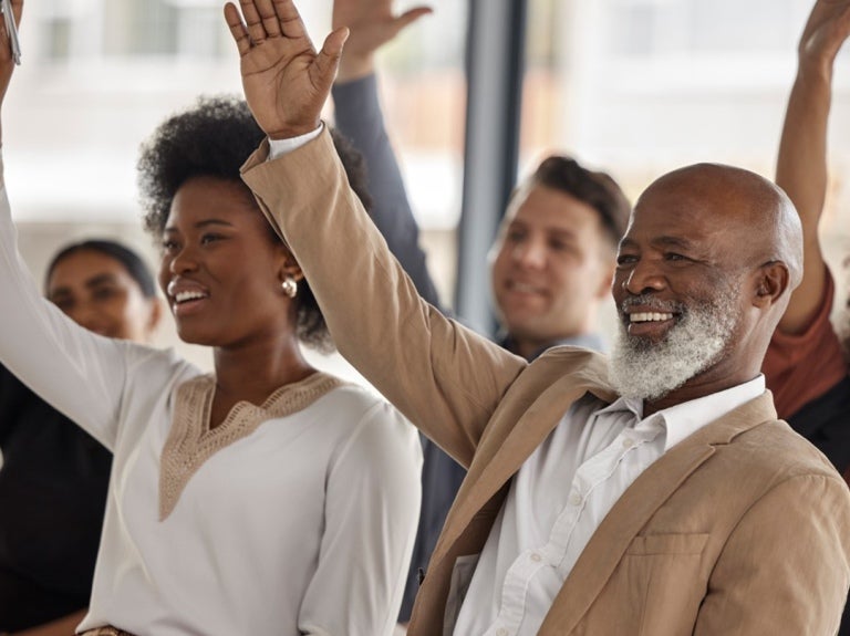 colleagues in a meeting raising their hands