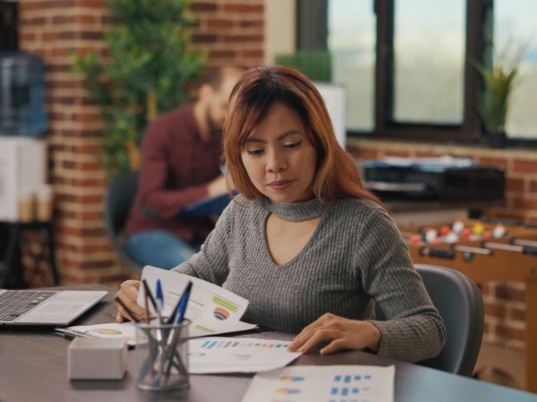 woman looking at graphs at her desk