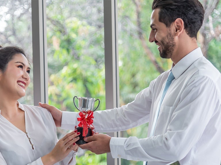 colleagues handing each other trophies
