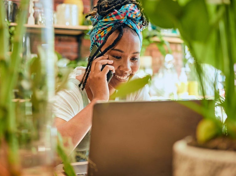 small business owner in front of her laptop and surrounded by plants 