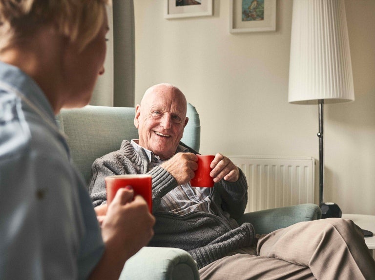 Resident of a care home chatting with nurse whilst drinking nescafe instant coffee