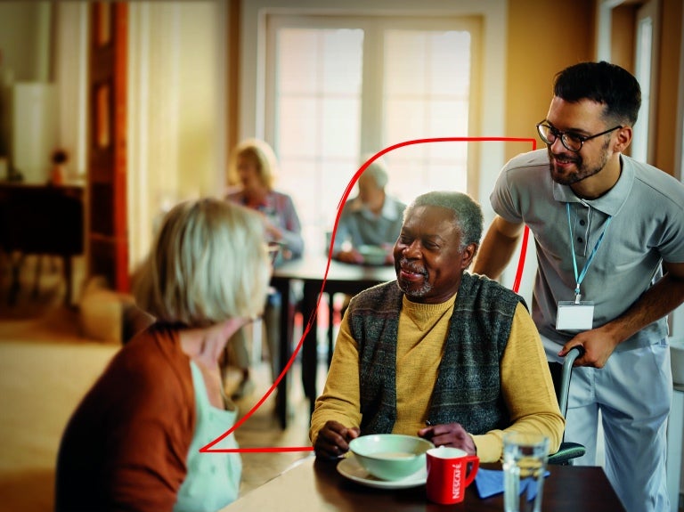 nescafe care home activity pack SS24 cover showing two care home resident, a man and a woman, talking with a staff member