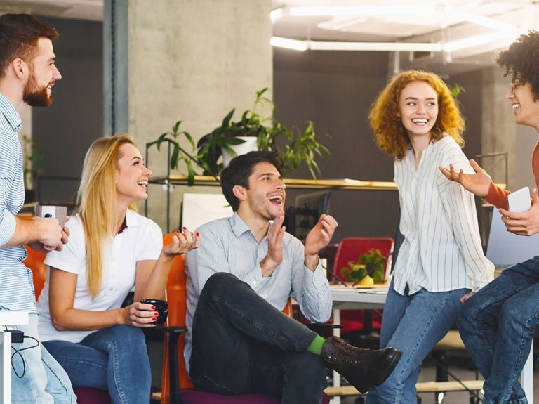 group of co-workers talking animatedly whilst drinking their coffee