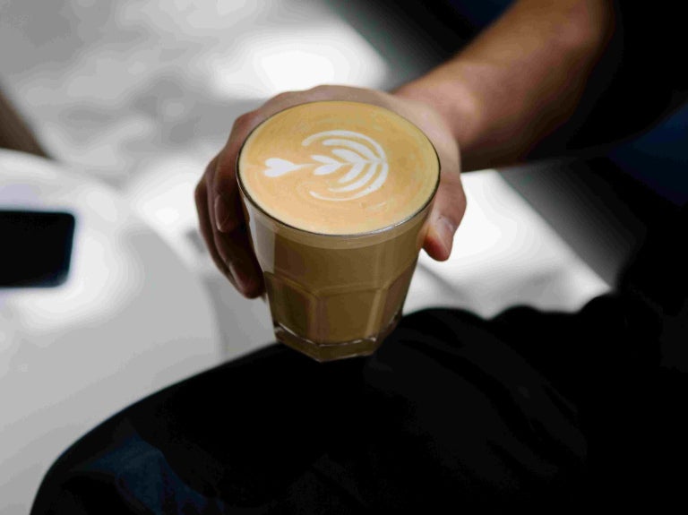 man holding latte in a cup