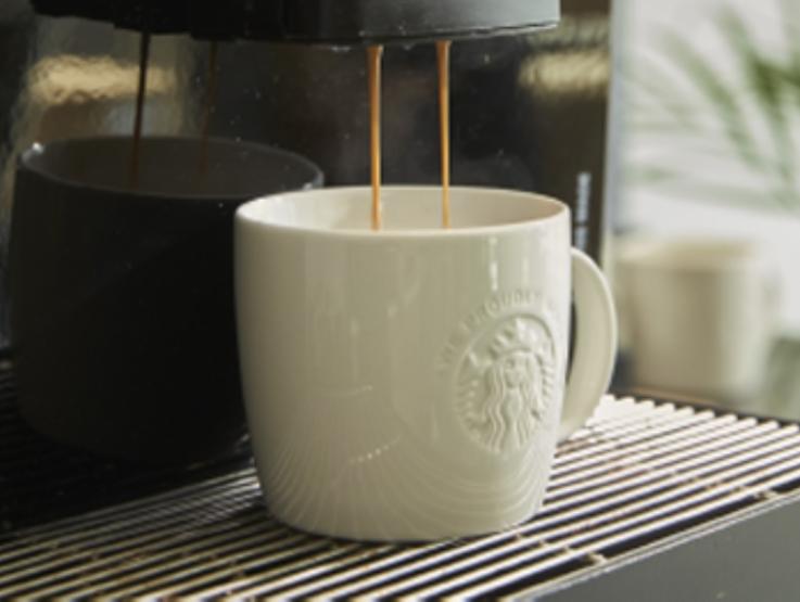 starbucks mug on coffee machine pouring coffee