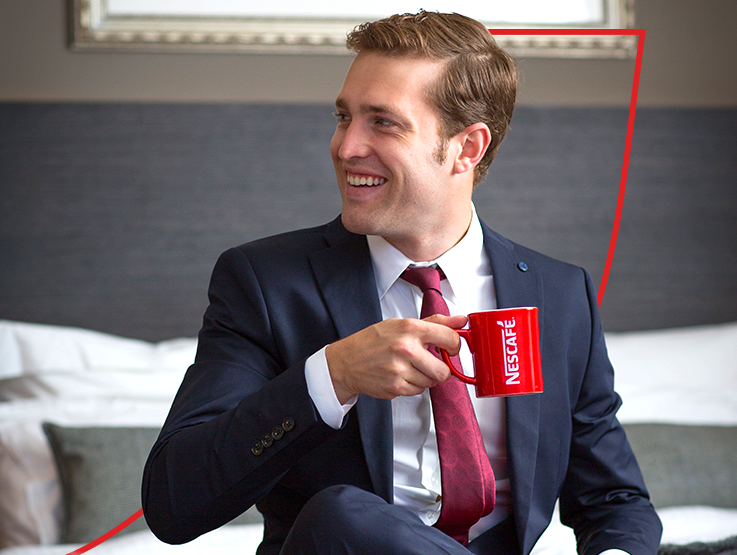 Businessman sat smiling with nescafe coffee