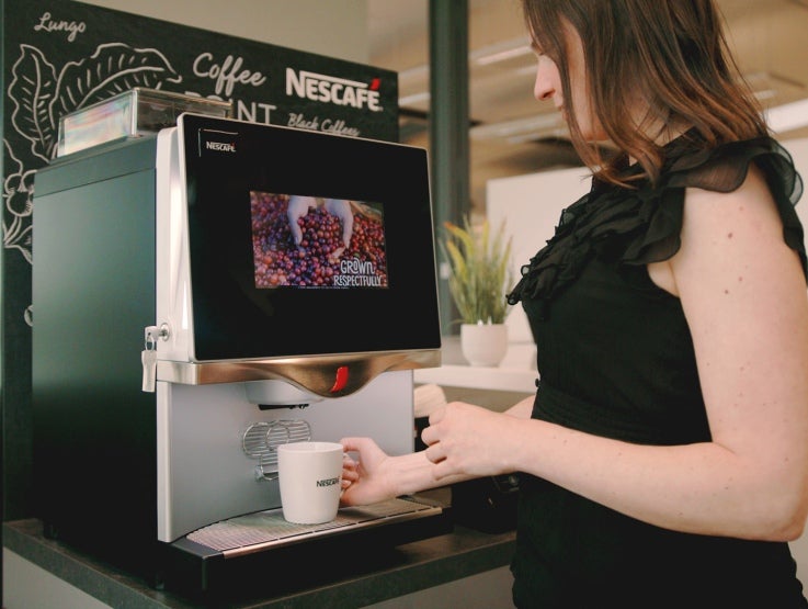 Office employee making a cup of coffee from a Nescafé coffee machine