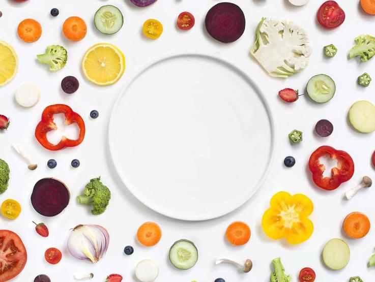 An empty plate surrounded by vegetables
