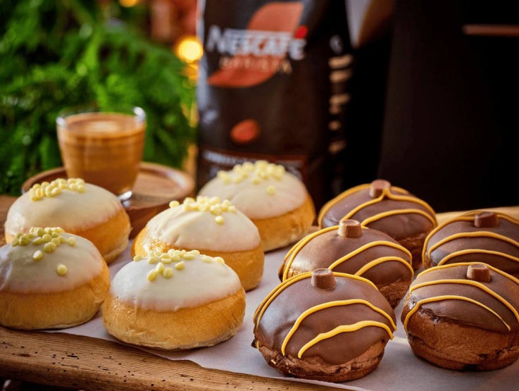 Iced doughnuts on a tray with espresso; white and chocolate, yellow sprinkles and drizzle