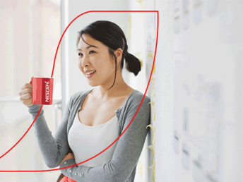 Female leaning back against a wall enjoying a mug of Nescafe coffee