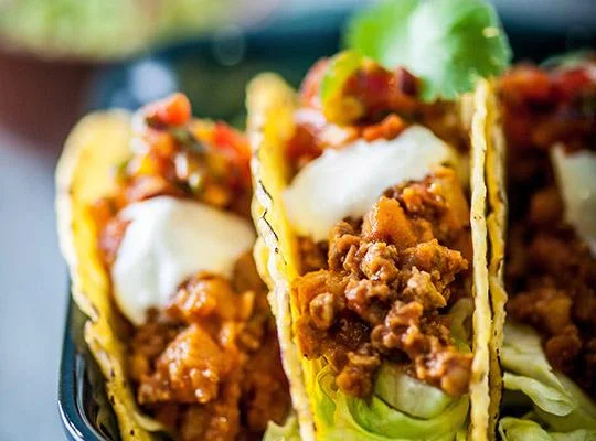 Quorn fruity chilli tacos topped with cheese, sour cream and lettuce