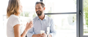 Work colleagues enjoying a conversation with hot beverages in hand