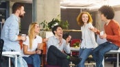 group of co-workers talking animatedly whilst drinking their coffee