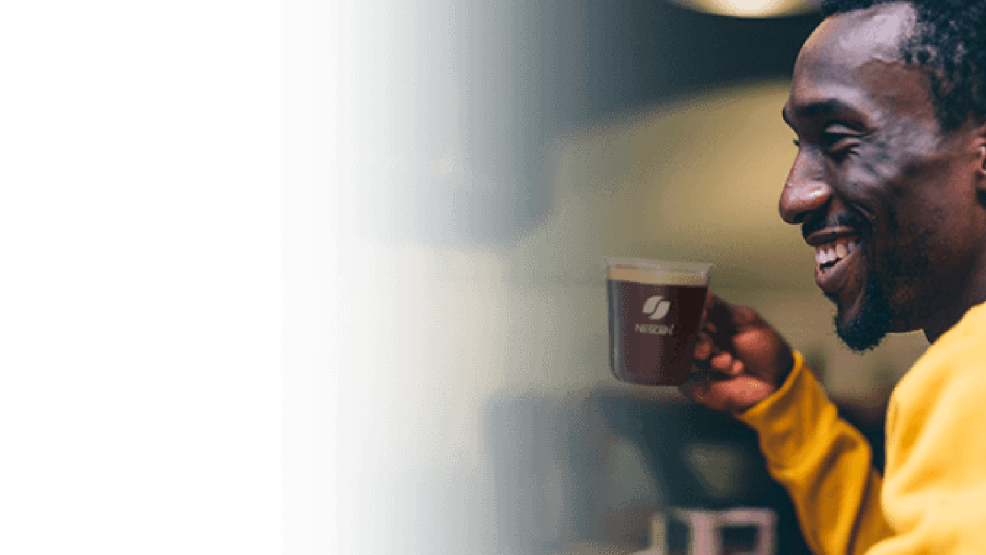 young man smiling and drinking NESCAFE