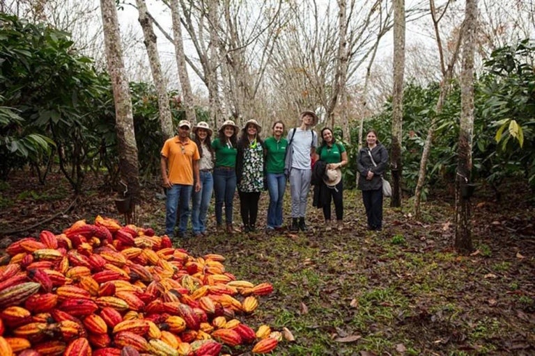 a-group-of-people-standing-in-front-of-a-pile-of-fruit